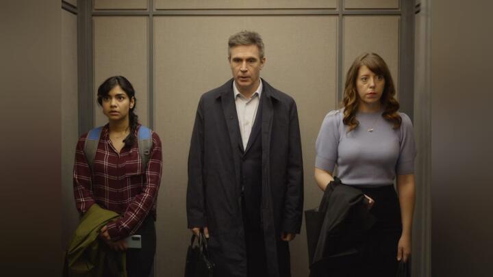 three people stand in a elevator
