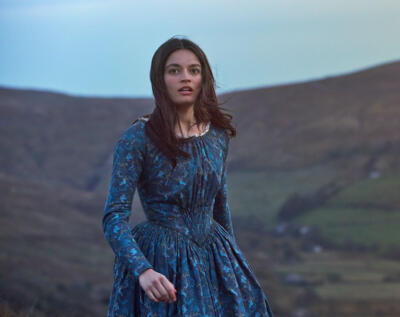 film still of an actress in period costume on a hillside